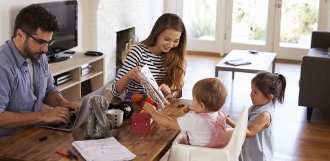 Vater-am-Laptop-während-Mutter-mit-Kindern-spielt